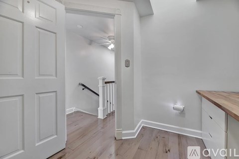 A white door is open to a hallway with a wooden floor.