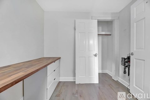 A white door is open to a hallway with a wooden floor.