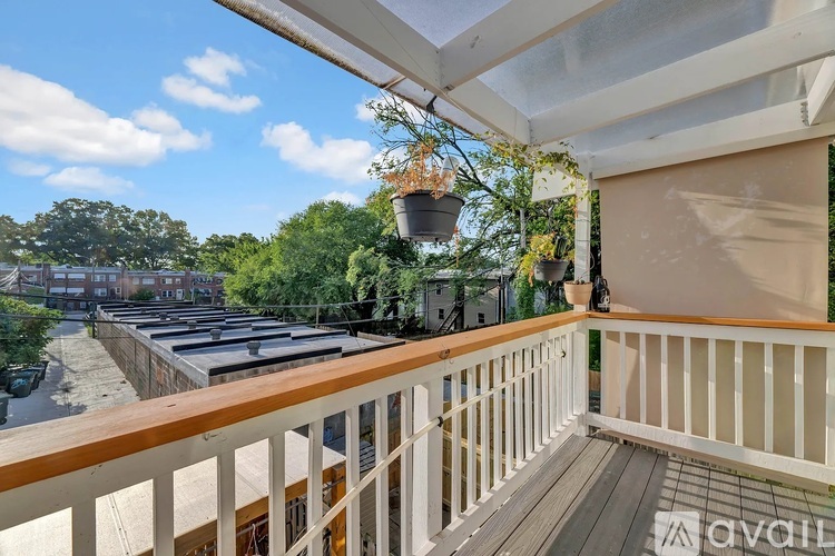 A balcony with a white railing and a view of a parking lot.