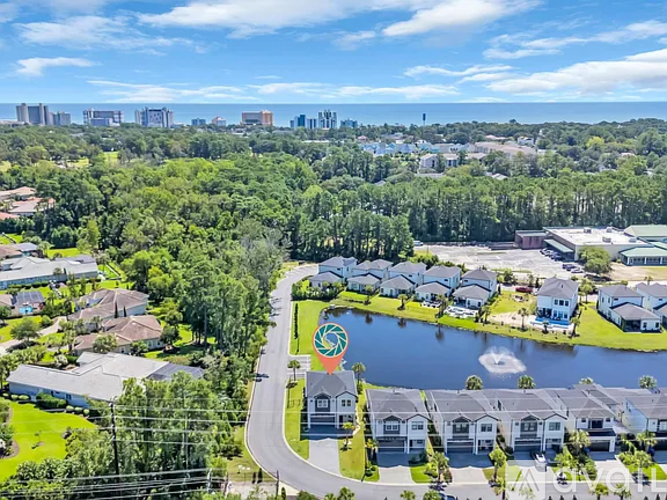 A bird's eye view of a residential area with a lake and a road.
