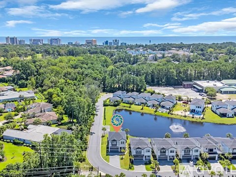 A bird's eye view of a residential area with a lake and a road.