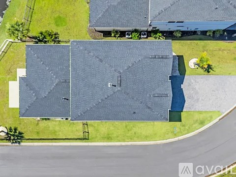 A large grey building with a flat roof is surrounded by a grassy area.