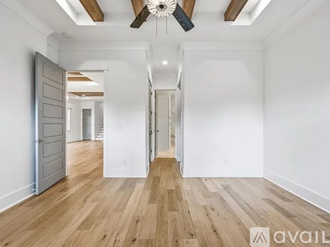 A spacious room with wooden floors and a ceiling fan.