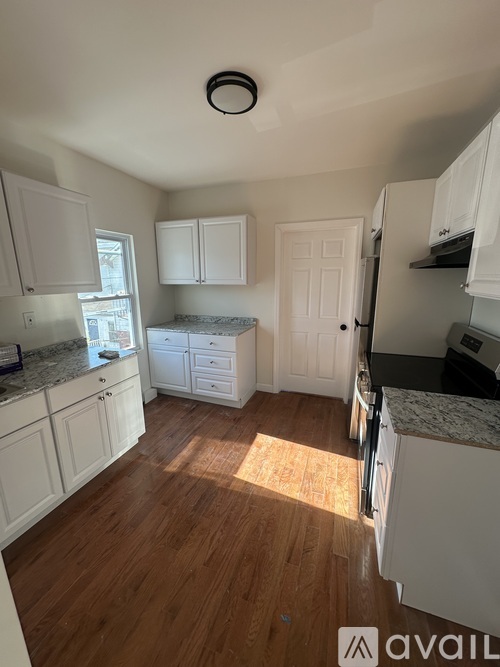 A kitchen with white cabinets and a wooden floor.