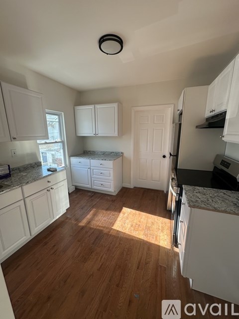 A kitchen with white cabinets and a wooden floor.