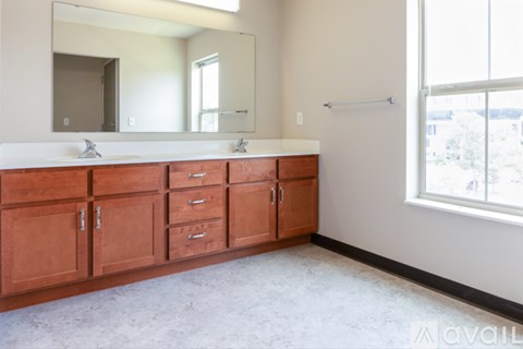 A bathroom with a white counter top and brown cabinets.