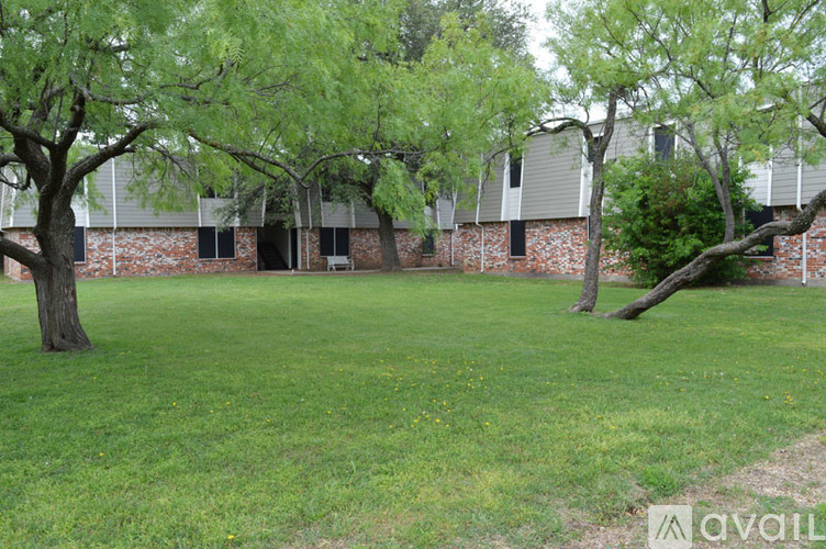 A grassy area with trees and a building in the background.