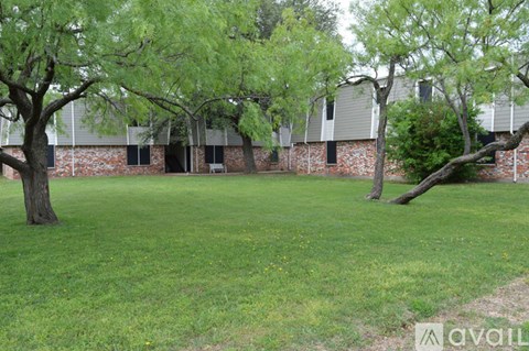 A grassy area with trees and a building in the background.