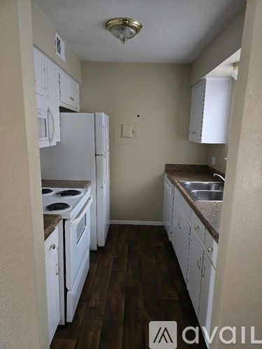 A kitchen with white appliances and brown wood floors.