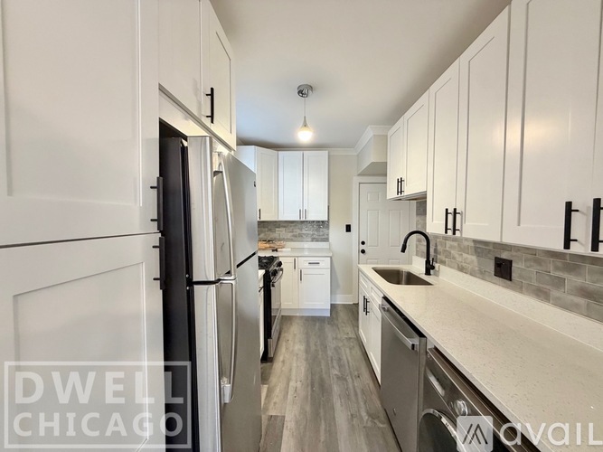 A kitchen with white cabinets and a black refrigerator.
