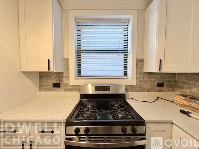 A modern kitchen with a stove top oven and white cabinets.