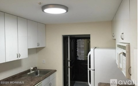A kitchen with white cabinets and a black door.