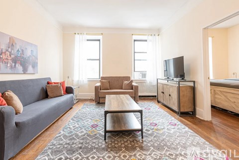 A living room with a grey couch, a brown sofa, a wooden cabinet, and a television.
