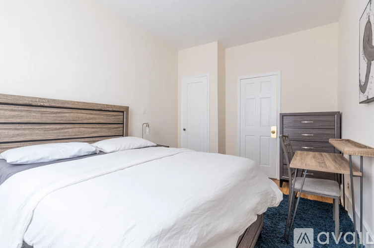 A bedroom with a bed, chair, and a wooden headboard.