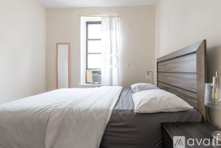 A bedroom with a large bed and a window with curtains.