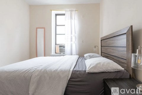 A bedroom with a large bed and a window with curtains.