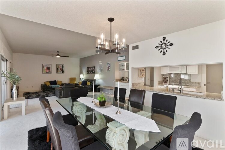A modern dining room with a glass table and chairs.