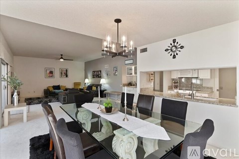 A modern dining room with a glass table and chairs.