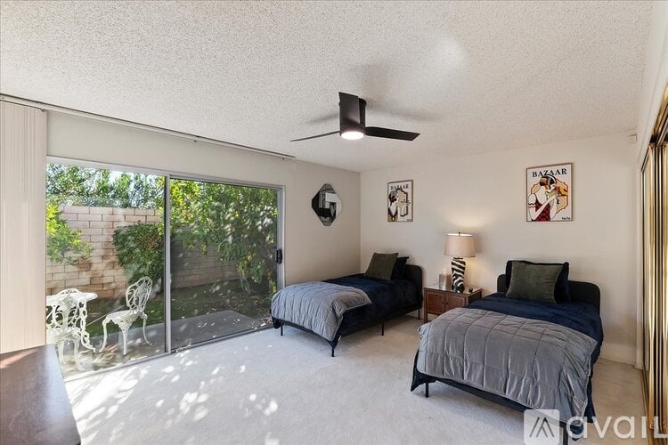 A bedroom with two beds and a ceiling fan.