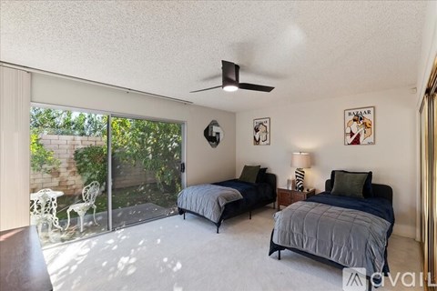 A bedroom with two beds and a ceiling fan.