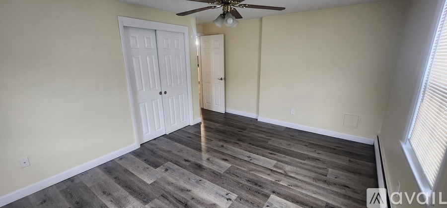 A room with a window and a fan on the ceiling.