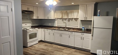 A kitchen with white cabinets and a white refrigerator.