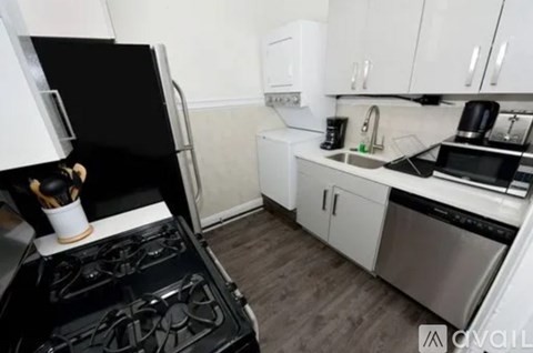 A black stove top oven in a kitchen with white cabinets.