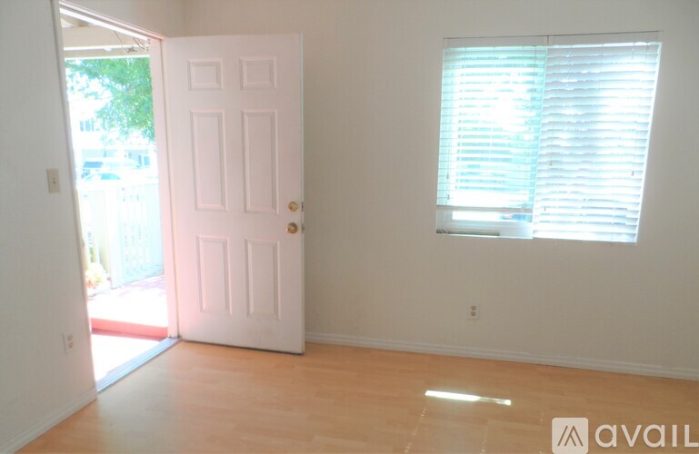 A white house with a porch and a red brick border.