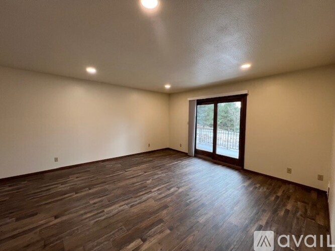 A room with wooden flooring and a sliding glass door.