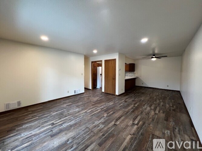 A spacious room with wooden flooring and a ceiling fan.