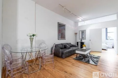 A living room with a glass table and a grey couch.