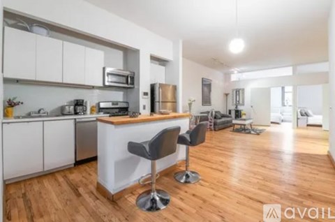 A kitchen with white cabinets and a wooden floor.