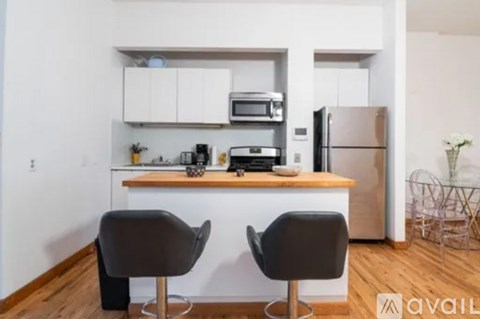 A kitchen with a refrigerator, microwave, toaster, and sink.