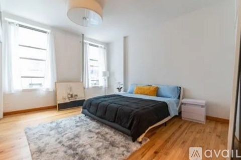 A bedroom with a large bed and a rug on the floor.