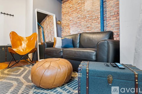 A living room with a brown leather couch, a blue suitcase, and a yellow chair.