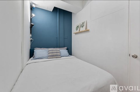A bedroom with a white bed and a blue wall.