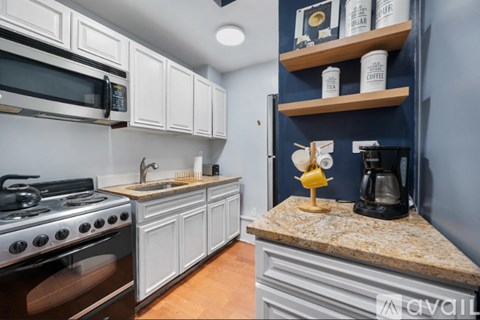 A kitchen with a stove top oven and a counter with a coffee maker and a banana.