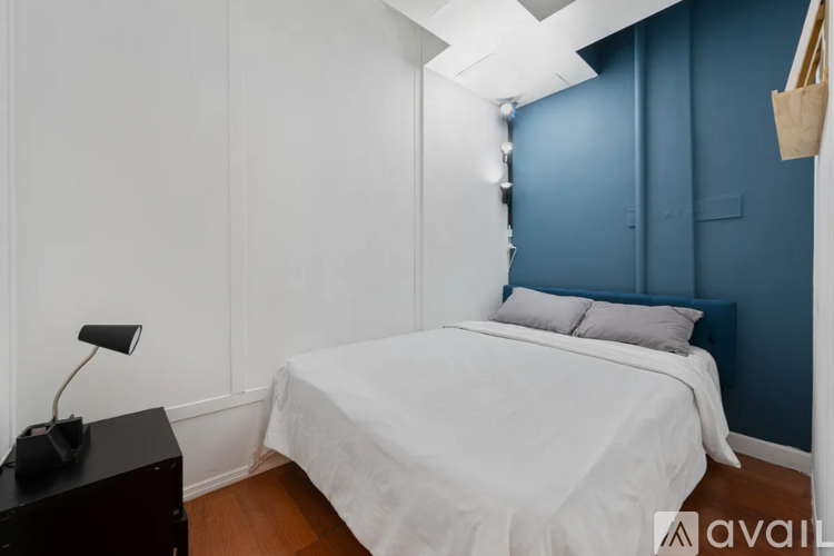 A bedroom with a white bed and a black desk.