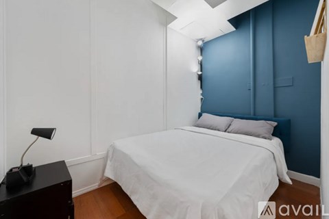 A bedroom with a white bed and a black desk.
