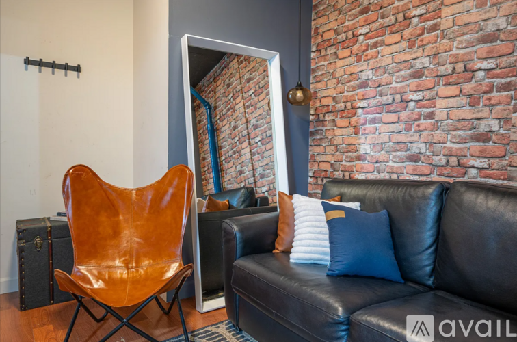 A brown leather chair sits in front of a black leather couch.
