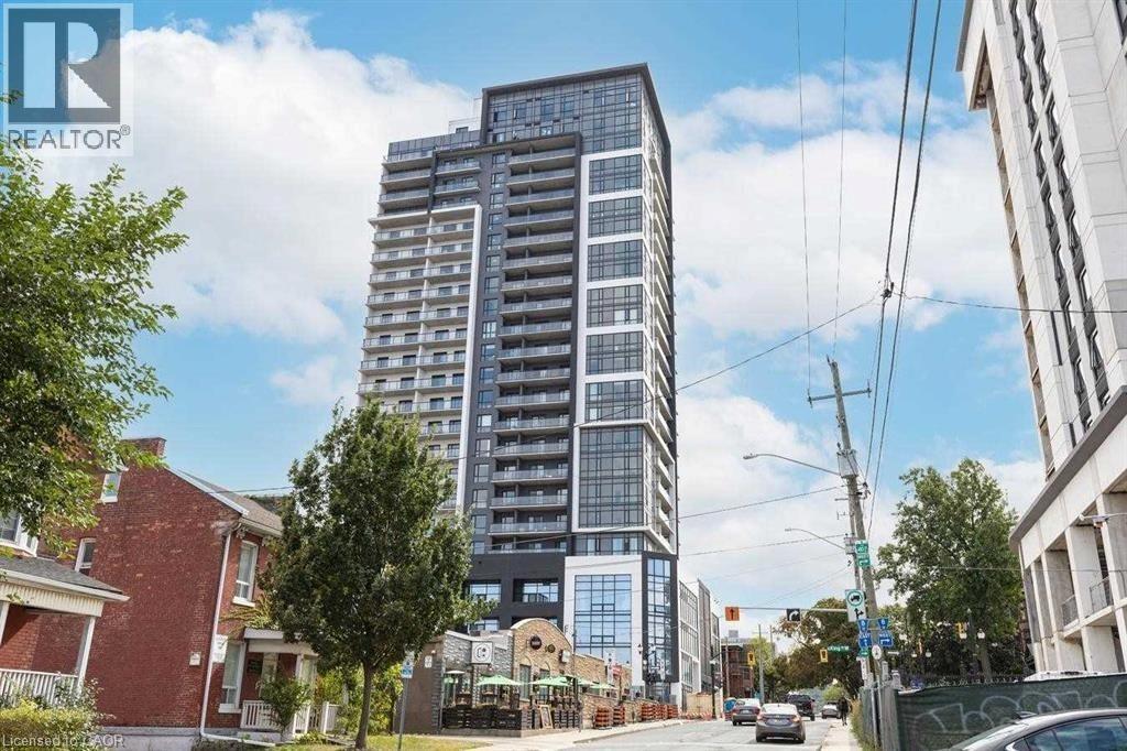 A tall building with many windows is in the middle of a street.