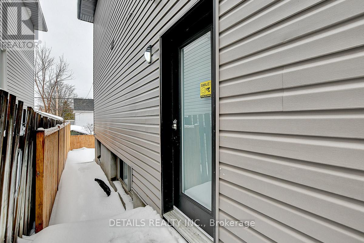 A snow-covered path leads to a black door with a yellow sign on it.