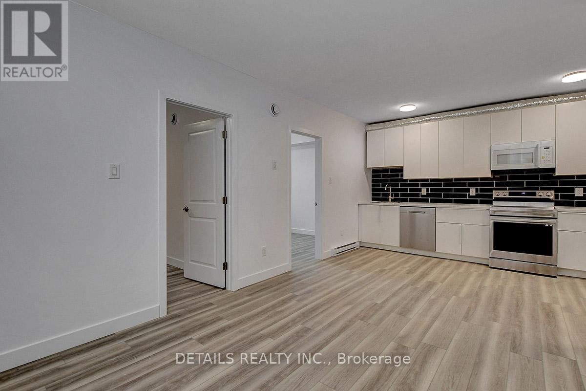 A realtor photo of a white room with a door and a kitchen area.