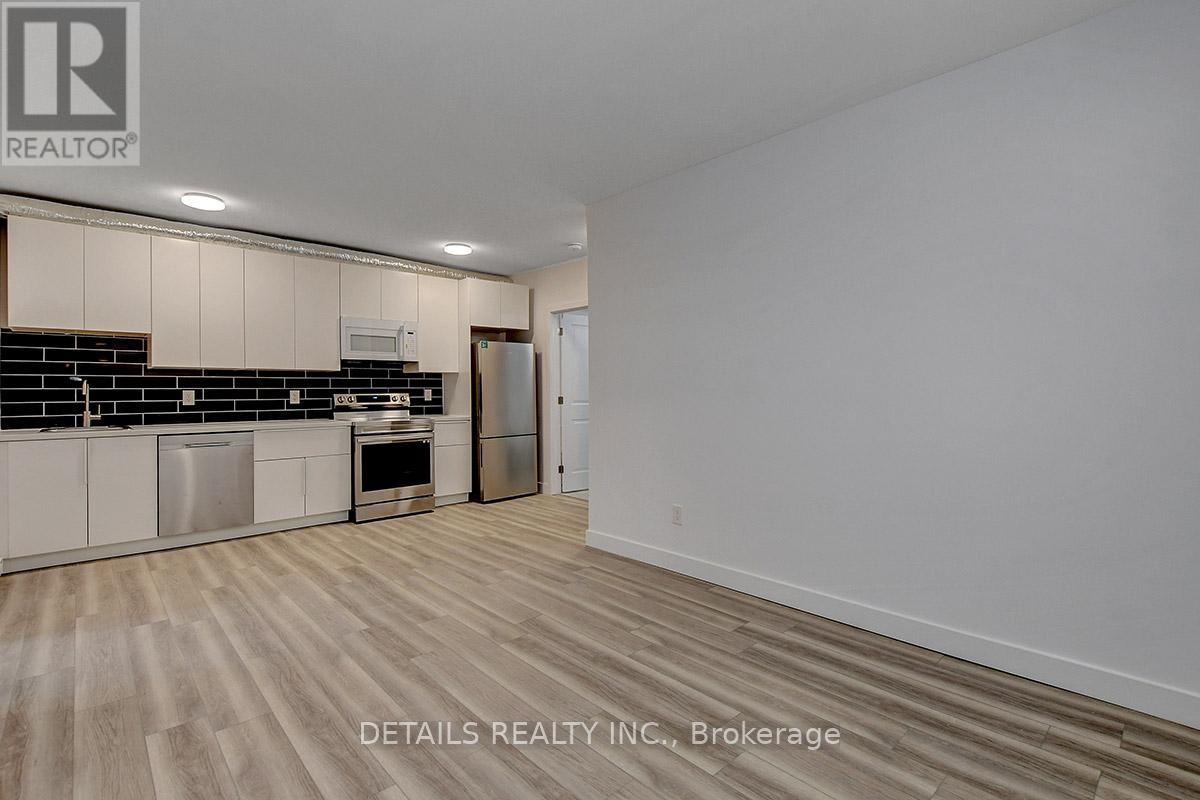 A spacious kitchen with wooden flooring and white walls.