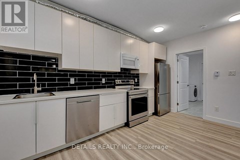 A kitchen with white cabinets and a black backsplash.