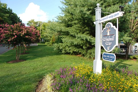 A sign for Windmill Way stands in a flower bed.