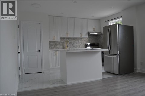 A kitchen with white cabinets and a black refrigerator.