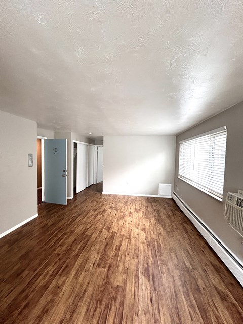 A room with wooden flooring and a window with blinds.