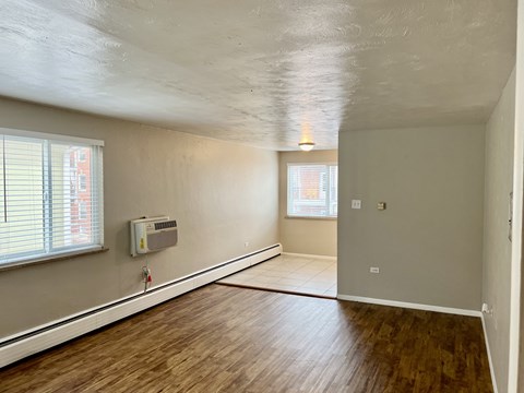 A room with wooden floors and a window with blinds.