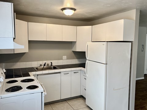 A kitchen with white appliances and cabinets.